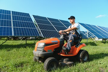 A man mows the grass near the solar panels. Green energy