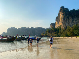 Tourists leaving Railay Beach, Thailand at sunset via water taxis. 