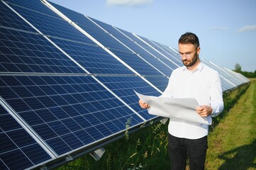 Male worker solar power plant on a background of photovoltaic panels.