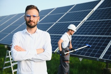man in white shirt standing near photovoltaic panels on sunny day in countryside