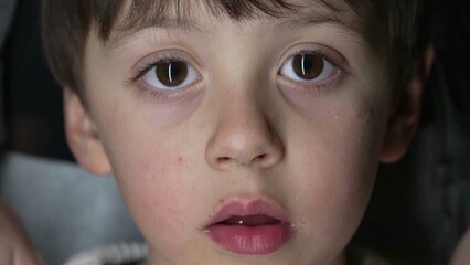 Child's close-up face looking at camera captured with macro lens. Portrait of young boy