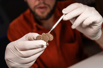 Restorer working late at night in the office restoring ancient coins. Restorer, conservation....