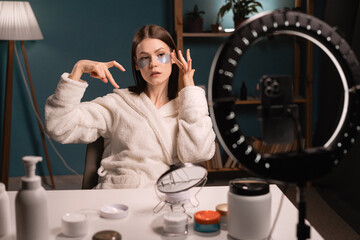 Concept of blogging about skin care and beauty. Young woman records video tutorial at home. Shoots broadcast live video to social network