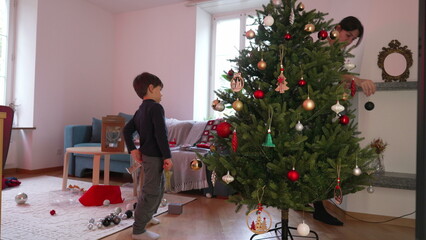 Candid Family Scene, Preparing for Christmas in Living Room - Mother and Child Decorating Tree