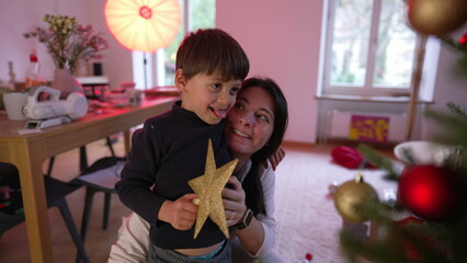 Child kissing mother in the cheek, togetherness scene of mom with son during Christmas season, celebrating holidays