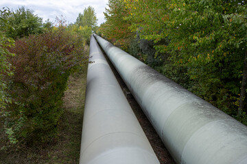 A colossal tube represents a thermal energy transfer infrastructure, central heating pipes enveloped in a robust metal thermal insulation jacket. Above-ground in European regions distribution energy 
