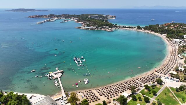 Aerial drone video of famous celebrity sandy beach Vouliagmeni in south Athens riviera with emerald crystal clear waters, Attica, Greece