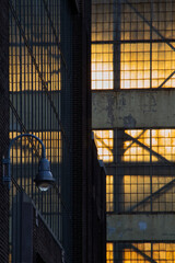 The setting sun shines through and reflects on old warehouse windows.
