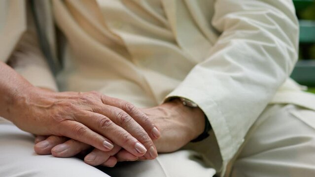 Close up unrecognizable wrinkled hand elderly old senior aged man and woman married couple husband wife holding hands outside love support family expressing empathy understanding relationship marriage