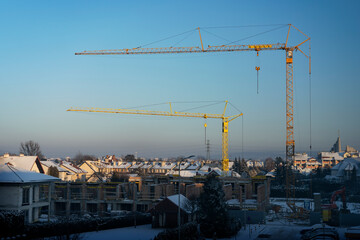 Construction of row houses (buildings under construction) in fastest growing economy of European Union - Poland. Rzeszow during winter sunset. Cranes concept. 