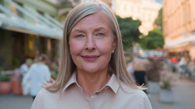 Close up portrait happy elderly mature grey-haired Caucasian elegant businesswoman lady female tourist woman looking camera outside city street business travelling holidays enjoy carefree retired life