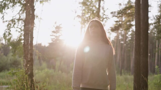 Woman walking in woods at back sunset. Upset young lady walks alone through sunny forest feeling useless. Finding solace from everyday stress in nature