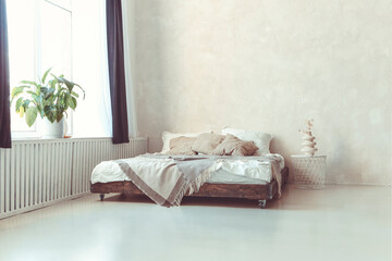 Stylish minimalist loft style bedroom interior with light concrete walls, king size wooden bed with pillows