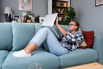 Obraz premium Young freelance business woman working at home on laptop as product strategy expert. Female expatriate remote work on internet on computer online for foreign company as web developer