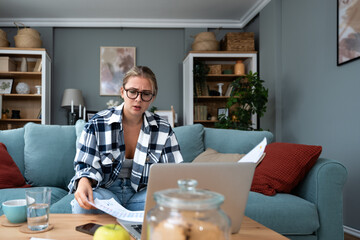 Young freelance business woman working at home on laptop as product strategy expert. Female expatriate remote work on internet on computer online for foreign company as web developer