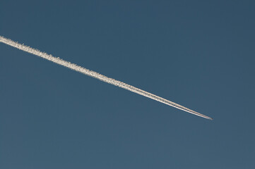Lecący samolot i jego ślad pozostawiony na niebie.