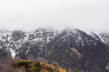 Mountain covered with snow and fog. Alpine landscape in Italy, Europe. Snow-capped mountains against blue sky