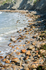 Rocky coastline. Sea wave background breaking sea water rocky shore rough turquoise water at Rimini, Italy. Seascape with sea horizon and clear deep blue sky.