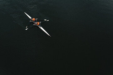 Canoe kayak with rowers on a background of dark water, top view.