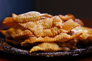 Frappe or chiacchiere with castagnole on a plate full of sugar. Typical Italian sweets of the carnival celebration. Cooked in all households and pastry shops. Also known as bugie lies