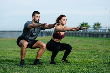 Fit young adult couple exercising outside training for running together in the park. Athletic male...