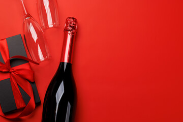 Champagne and gift: Celebratory duo on a red background with text space