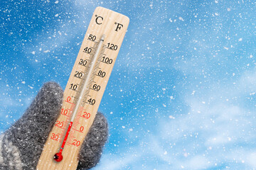White celsius scale thermometer in hand. Ambient temperature minus 13 degrees celsius