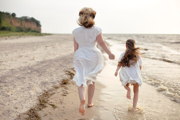 Mother and daughter running by the sea