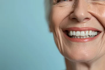 Fotobehang Smiling elderly person with smooth white teeth implants. Close up portrait of female mouth on pastel blue background, banner with copy space. Positive senior woman © Lazy_Bear