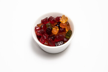 Colorful gummy candies in a white cup on a white background
