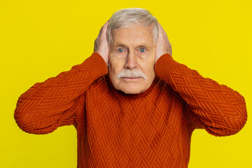 Don't want to hear and listen. Frustrated annoyed irritated elderly old man covering ears gesturing...