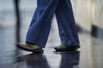 Legs of a girl in wide blue pants and bright sports shoes, close up of training running shoes,...