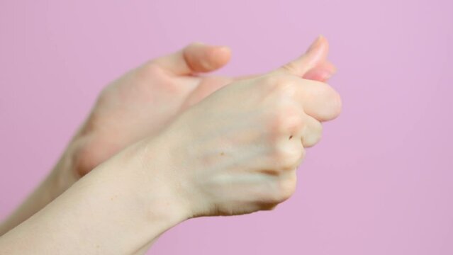 Self-massage of hands. Woman smears cream on her hand skin. Female hands care. Hands close up on pink background. Hand protection from frostbite