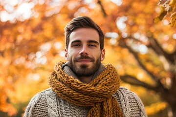 Standing amidst autumn foliage A man in a cozy sweater and scarf captures the warm essence of the fall season
