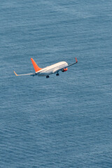 Commercial plane flying over the blue sea.