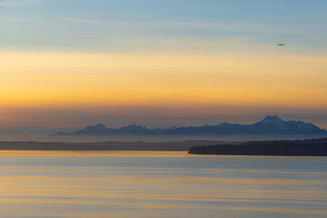 A colorful sunset lights up the clouds in the sky over the Pacific Northwest with mountains in the background