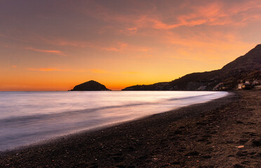 tramonto visto da una delle spiagge dell'isola d'Ischia, acqua con effetto seta illuminata dai...