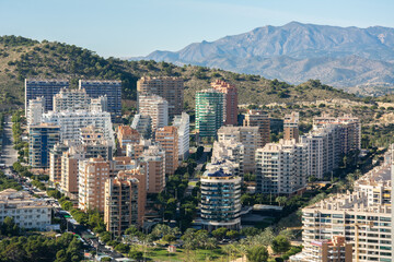 Obraz premium Multi floor residential buildings on a hill with mountains at the back in Benidorm resort town of Spain