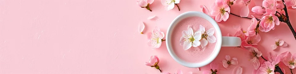 Deurstickers White sakura latte in cup on pink surface with cherry blossoms. Panoramic still life photo. Springtime and café concept. Design for banner, header with copy space. Spring composition with flowers © dreamdes