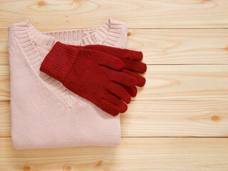 Pink sweater and gloves on wooden background