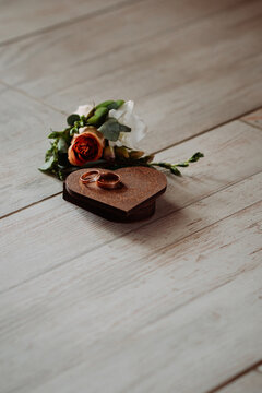 The image contains a single red rose and a ring placed on a wooden table 5366.
