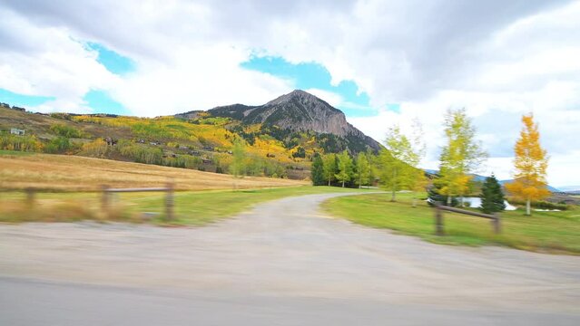 Crested Butte, Colorado village town car vehicle driving shot side view in autumn at Rocky mountains by buildings houses