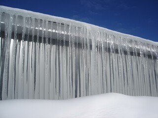icicles on a long line over a snow covered roof