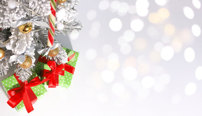 New Year's and Christmas. on a white background there is a Christmas tree with white needles and under the tree there are gifts in green wrapping paper and a red bow