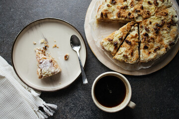 Homemade pie on concrete table. Top view of bitten piece of pie with spoon on plate and cup of black coffee