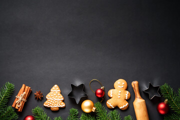 Christmas baking background. Gingerbread cookies, spices and Christmas decorations at black. Top view with space for text.