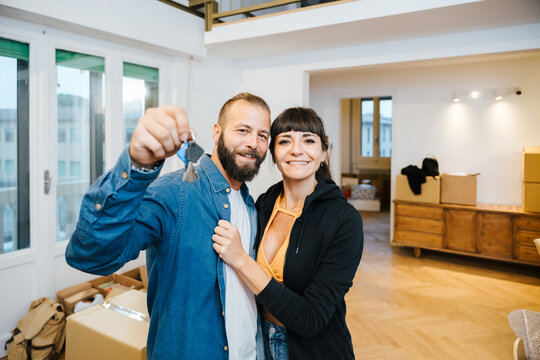 Happy engaged couple showing keys to new house and smiling