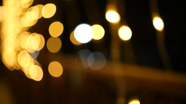 Flashing garland lights without focus, stock video. Festive golden glitter bokeh decor on the street. LED lighting background texture in slow motion.