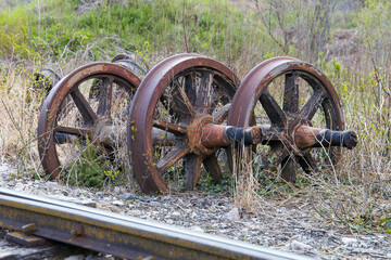 old train wheels rusting beside rails in the grass