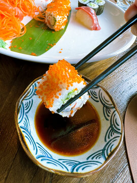 piece of suchi roll, Japanese food eaten with chopsticks over soy sauce